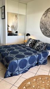 Bleu ocean في Saint-Paul: سرير أزرق مع وسائد سوداء وبيضاء في غرفة النوم