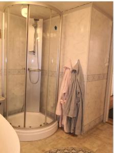 a shower in a bathroom with a robe on the wall at Studioleilighet i kjeller ved stranden og hvalsenter NB Må vaskes etter endt leie eller betale rengjøringshjelpen 500 kr in Andenes +6 photos