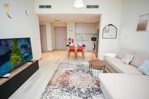 a living room with a couch and a tv and a table at Champagne pink Apartment - Yas Island in Abu Dhabi