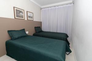 a bedroom with two green beds and a window at Cardeal 403C - Aconchegante apartamento na praia de Bombas - 2 dormitórios 5 pessoas - (Consultar serviços de roupa de cama e banho) in Bombas