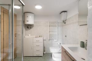 a white bathroom with a toilet and a sink at DOLF - Villa Ombrosa in Isola