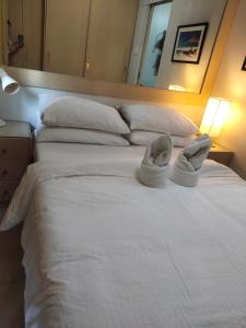 ein großes weißes Bett mit zwei Paar Schuhen drauf in der Unterkunft Sea Residence Finest in Manila
