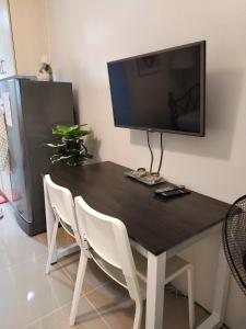 einen schwarzen Tisch mit weißen Stühlen und einen Flachbild-TV in der Unterkunft Sea Residence Finest in Manila