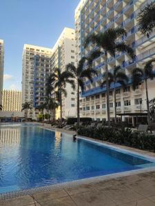 ein großer Pool mit Palmen und Gebäuden in der Unterkunft Sea Residence Finest in Manila