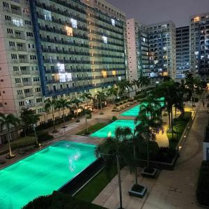 einen Blick über einen Pool mit Palmen und Gebäuden in der Unterkunft Sea Residence Finest in Manila