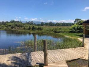 a wooden dock on a river with a view of a field at Pousada Xaxá in Guarda do Embaú