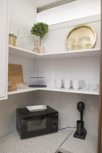 a microwave on a shelf with bowls and dishes at STAY Glam Skin Studio in Nicosia