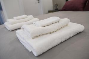 four white towels are stacked on a bed at STAY Glam Skin Studio in Nicosia
