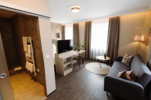 uma sala de estar com um sofá e uma secretária com uma televisão em Hotel Säntis em Munique