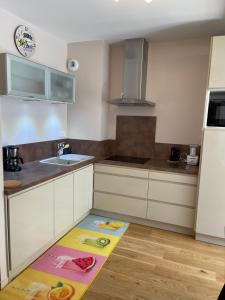 eine Küche mit weißen Schränken und einem Küchenteppich auf dem Boden in der Unterkunft Le B4 - Résidence La Montille in Le Mont-Dore