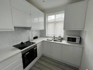 a white kitchen with white cabinets and a microwave at Spacious Modern Flat in Mitcham in Mitcham