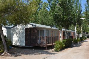 a row of cottages on a street with trees at Camping Valencia el Saler in El Saler