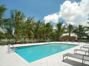 a swimming pool with chairs and palm trees at Fairfield Inn & Suites by Marriott Fort Lauderdale Northwest in Tamarac