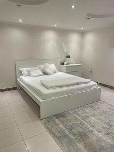 a white bedroom with a large white bed with a rug at شقة فاخرة بقفل ذكي - Luxury apartment in Riyadh