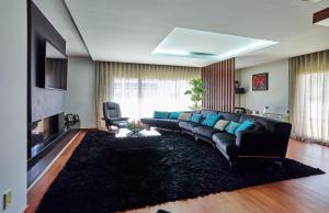 een woonkamer met een zwarte bank en een open haard bij Fonte Seca GuestHouse in Leiria