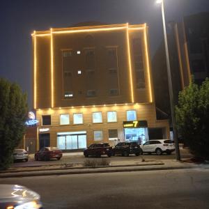 a lit up building with cars parked in a parking lot at قصر اباهي للوحدات السكنية in Al Jubail