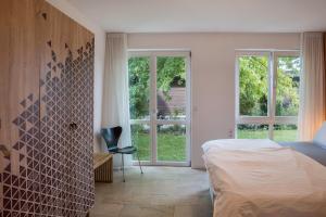 a bedroom with a bed and a chair and windows at Ferienwohnung Tödiblick in Wangen im Allgäu