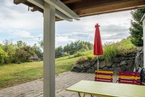 - une table de pique-nique avec un parasol rouge sur la terrasse dans l'établissement Ferienwohnung Tödiblick, à Wangen im Allgäu