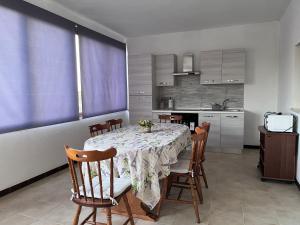 mesa de comedor con sillas y cocina en Il Sole en Donigala Fenughedu