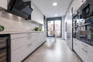 a kitchen with white cabinets and a large window at LUJOSO CHALET CON PISCINA PRIVADA, JARDIN Y DOMÓTICA EN PUERTA DE HIERRO in Madrid