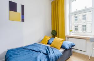 a bedroom with a bed with blue sheets and yellow pillows at Kawalerka w Śródmieściu 24 in Łódź