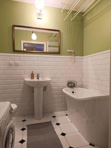 a bathroom with a sink and a tub and a mirror at Apartament Parkowy 24h in Łomża