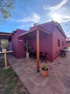a purple house with a table and chairs on a patio at Hostel Ruta76 in Sierra de la Ventana