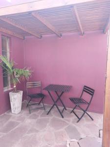 a patio with two chairs and a table and a purple wall at Hostel Ruta76 in Sierra de la Ventana