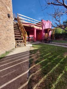 a pink building with a staircase next to a yard at Hostel Ruta76 in Sierra de la Ventana