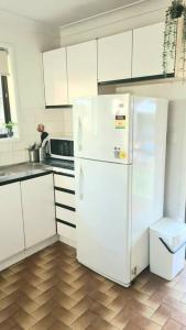 a kitchen with white cabinets and a white refrigerator at Guesthouse in fantastic location in Brisbane