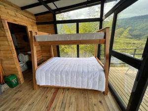 Bett in einer Hütte mit einem großen Fenster in der Unterkunft El Templo del Agua in San Rafael