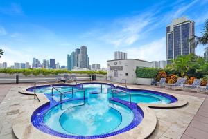 a swimming pool on the roof of a building with a city at The Palms! Direct water view corner condo in Miami