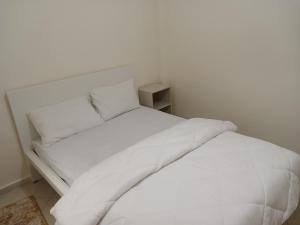 uma cama branca com lençóis e almofadas brancos em Chambre privative dans un appartement partagé em Casablanca
