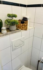 a white tiled bathroom with a toilet and a basket at AyCatcherHomes Top Lage charmante Atmosphäre in ruhiger Altstadt Marburgs Apartment Sirius in Marburg an der Lahn