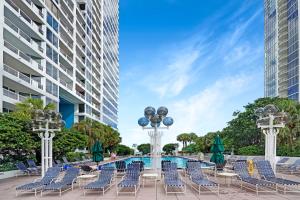 a group of chairs and a pool in front of a building at The Palms! Direct water view corner condo in Miami
