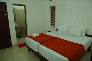 um quarto com uma cama grande e um cobertor vermelho em Grace Mary Residency em Nedumbassery