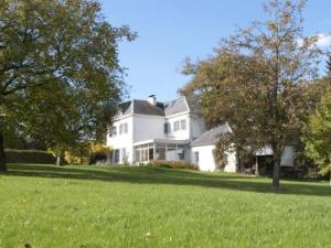 una gran casa blanca en un campo de hierba en Le Chaperon Villa, en Tellin