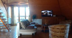 a living room with two chairs and a television at Komfort Apartman in Eger