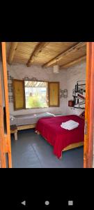 1 dormitorio con cama roja y ventana en Posada 50 Nudos al paso aguanegra en Rodeo