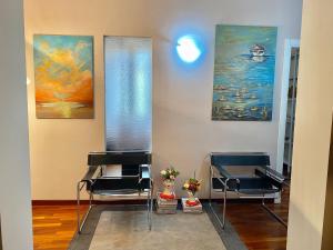 a room with three chairs and paintings on the wall at Le Camere di Mara in Foligno