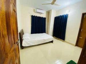 a bedroom with a bed and blue curtains at Cheapest Apartment in Dhaka in Dhaka