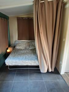 Bett in einem Zimmer mit Vorhang in der Unterkunft chalet en bord de rivière (saône) in Rigny