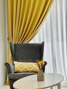 a living room with a chair and a table with a vase at Hanna Homestay Apartment for Muslim in Tanah Rata