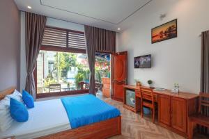 a bedroom with a bed and a tv and a window at Hotel Blue Dragon in Phú Quốc