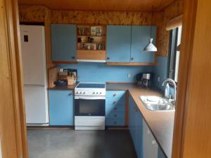 a blue kitchen with white appliances and blue cabinets at Holiday home Rødvig Stevns II in Rødvig