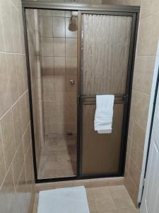 um chuveiro com uma porta de vidro com uma toalha em Gran Hotel Desamparados em Desamparados