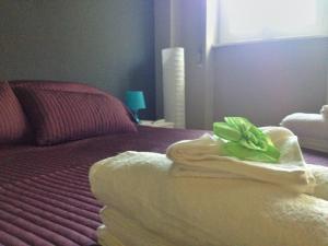 ein Bett mit einem Handtuch mit grünem Bogen drauf in der Unterkunft Milano Colletta Apartment in Mailand