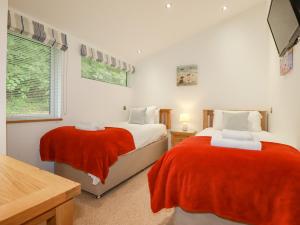 a bedroom with two beds with red blankets at 9 Valley View in Looe