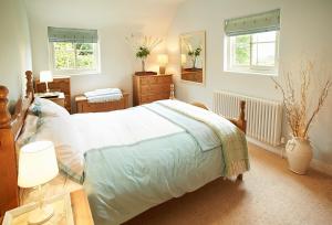 a bedroom with a bed and a desk and two windows at The White House in Little Weighton