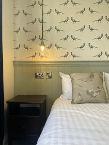 a bedroom with a bed with a bird pattern on the wall at The Horseshoe & Castle in Rochester